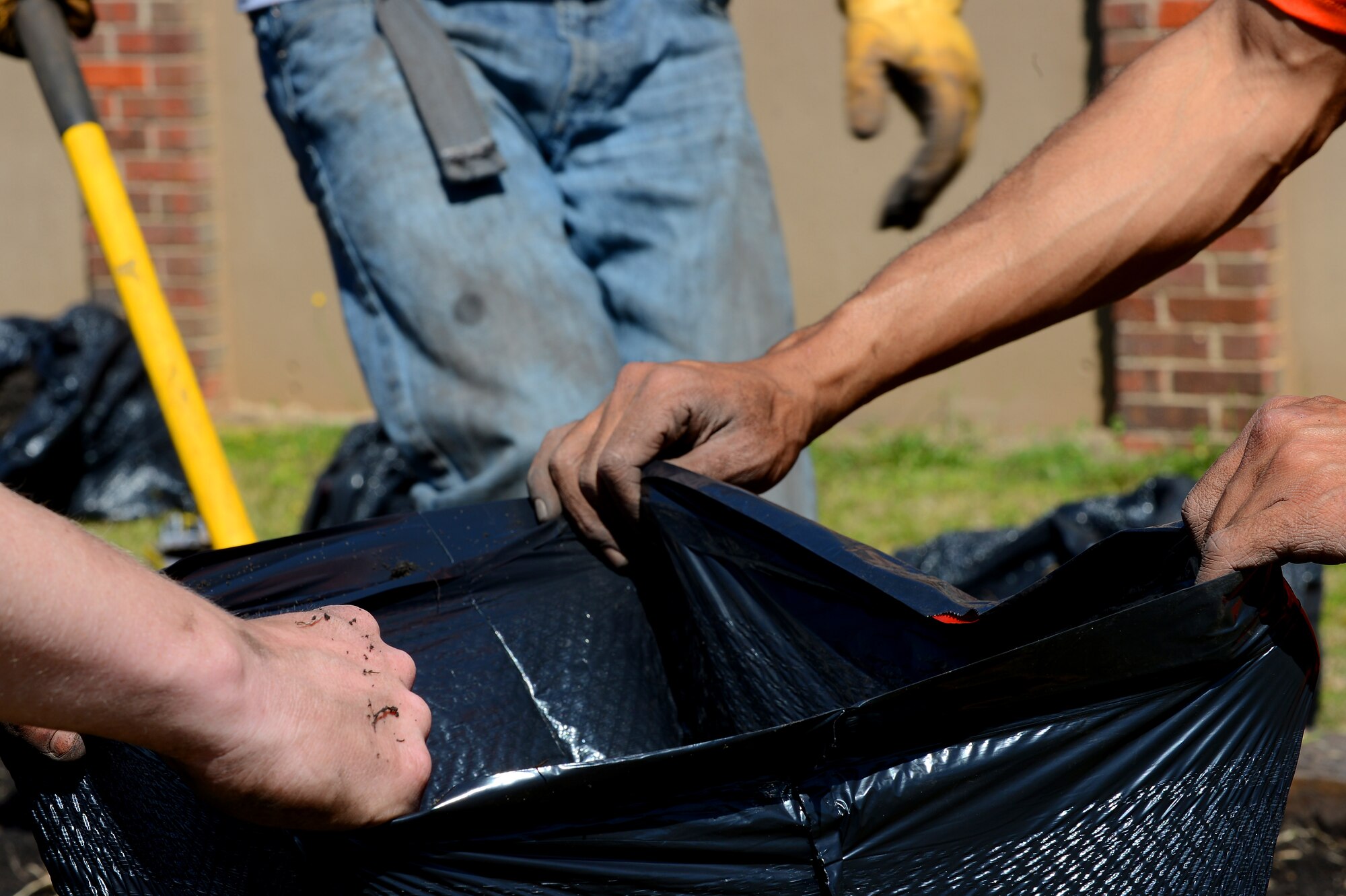 U.S. Air Force Airmen assigned to the 20th Civil Engineer Squadron dispose of weeds into a garbage bag at Hillcrest Middle School, Sumter, S.C., March 19, 2013.  The Airmen volunteered to help plant vegetables for the study of photosynthesis during the spring. (U.S. Air Force photo by Airman 1st Class Nicole Sikorski/Released)