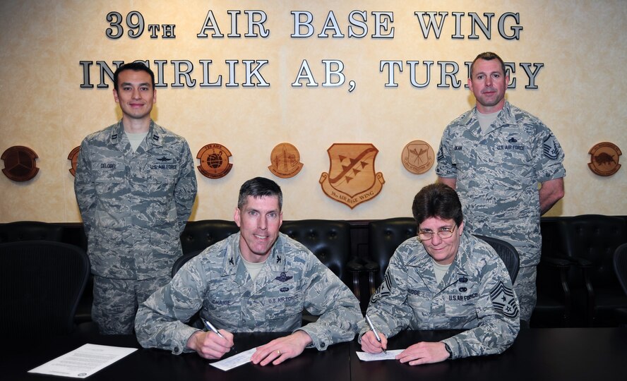 Col. Chris Craige, 39th Air Base Wing commander, and Chief Master Sgt. Nancy Judge, 39th ABW command chief, sign their Air Force Assistance Fund donation cards March 25, 2013, at Incirlik Air Base, Turkey. The AFAF is comprised of four charity organizations that directly support Airmen and their families in times of need. (U.S. Air Force photo by Senior Airman Anthony Sanchelli/Released)