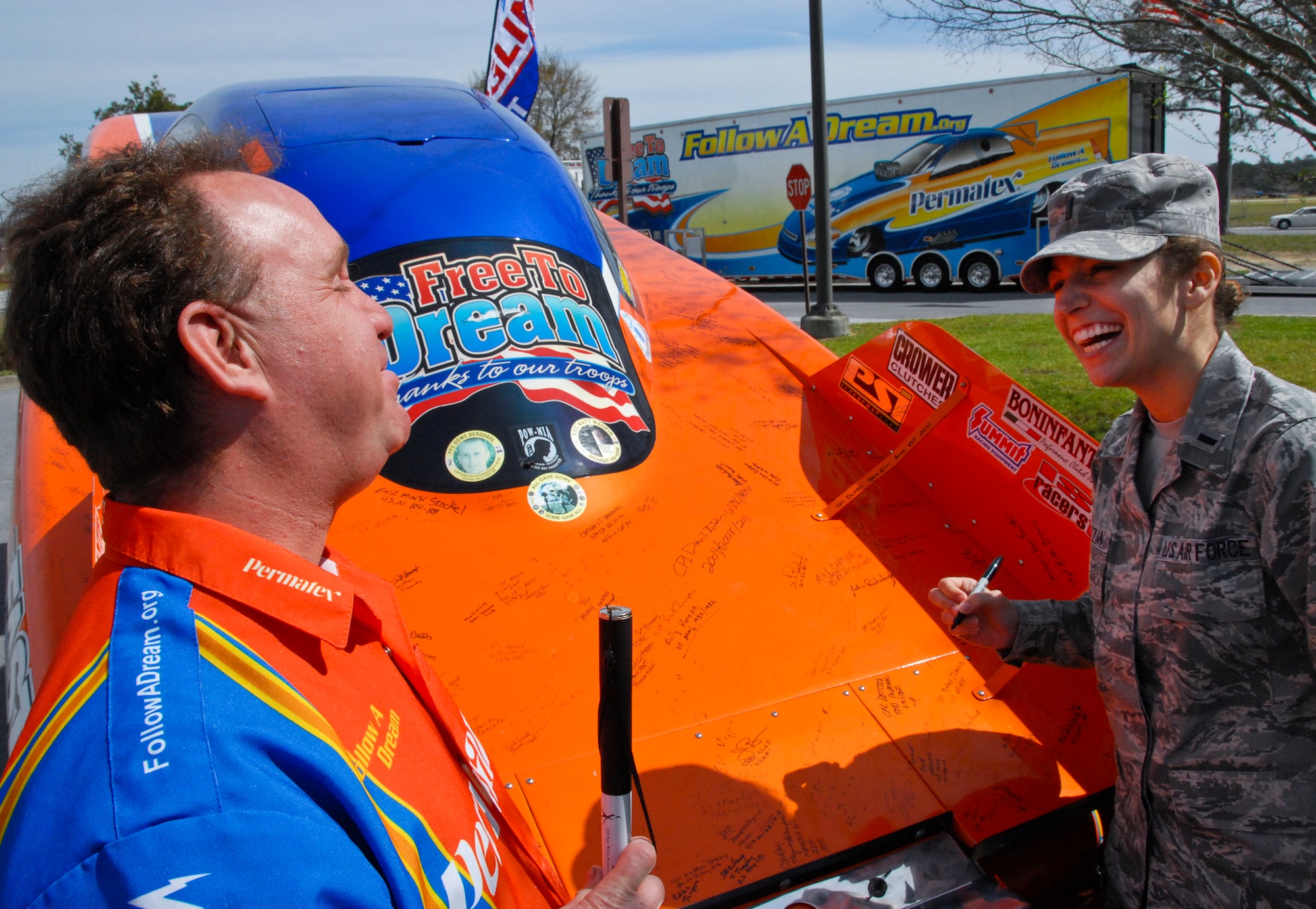 Jay Blake and 1st Lt. Sara Ruzzin, a member of the Air Force Research Laboratory, share a laugh as she signs Blake’s drag racing team car, on display at The Crossroads at Eglin Air Force Base Fla., March 20.  Blake, who lost his sense of sight, smell and taste in a tire explosion accident in 1997, now owns one of the country’s top drag racing teams.  He brought his inspiring ‘Follow A Dream’ message of perseverance to Eglin’s military members and civilians as part his commitment to community outreach.  (U.S. Air Force photo/Kevin Gaddie)  