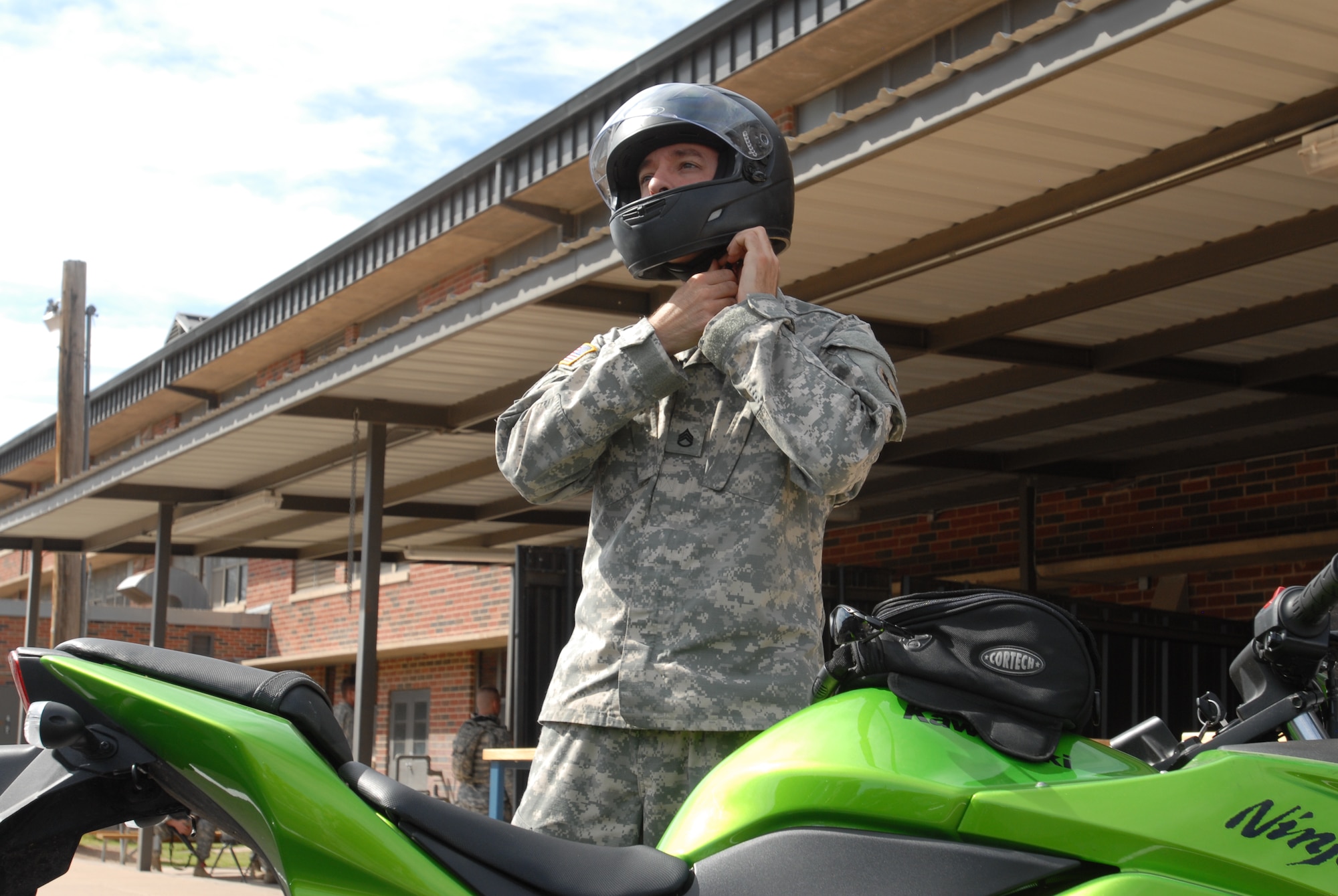 GOODFELLOW AIR FORCE BASE, Texas – A motorcyclist properly puts on his personal protective equipment before riding on his motorcycle March 22 at the Army Battalion here.  Proper PPE includes a helmet fastened under the chin; a full face shield or eye protection; long trousers; a long sleeved shirt or jacket; full-fingered gloves or mittens and sturdy, over-the-ankle footwear.  (U.S. Air Force photo/ Airman 1st Class Breonna Fields)