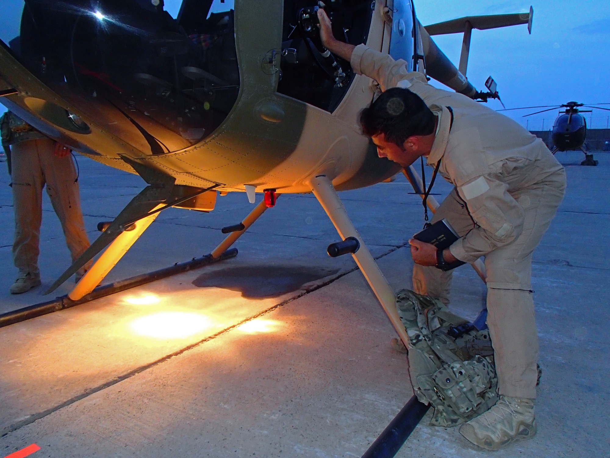 A pilot trainee in the Afghan Air Force checks the lights and infrared equipment on an MD-530 helicopter prior to a night vision goggles training mission March 19, 2013, at Shindand Air Base, Afghanistan. The current class going through NVG training, with eight students, is the largest class as well as only the third class to go through the training at SAB. NVG training is taught by air advisors from the 444th Air Expeditionary Advisory Squadron. (U.S. Air Force photo/Capt. Anastasia Wasem)