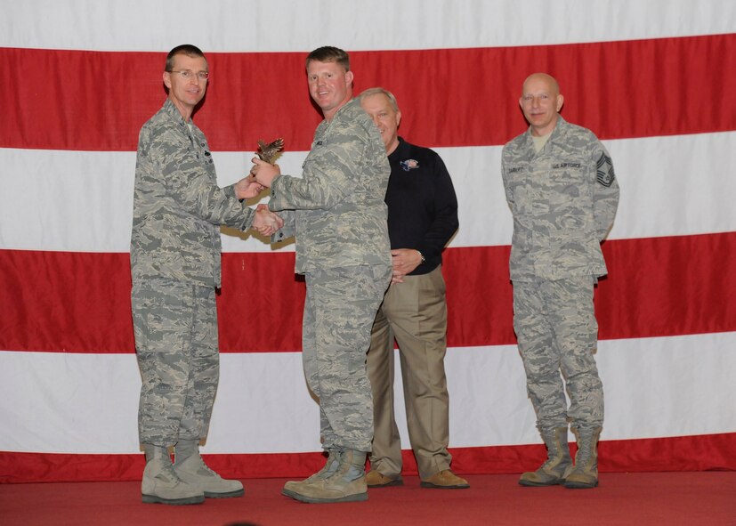 Captain Arne R. Gjere, 325th FW Munitions Flight commander, accepts the 325th Fighter Wing Munitions/Missile Maintenance Company Grade Manager Award from Col. Curtis Hafer, 325th Maintenance Group commander, and Chief Master Sgt. Terry Gabbert, 325th MXG superintendent, and retired ninth Chief Master Sergeant of the Air Force, Chief Master Sgt. James Binnicker, during the 2012 Maintenance and Staff Professionals of the Year banquet in Hangar 1 March 15. The MPOY banquet recognizes the achievements of the maintenance group and honors maintenance professionals each year. (U.S. Air Force photo by Chris Cokeing) 
