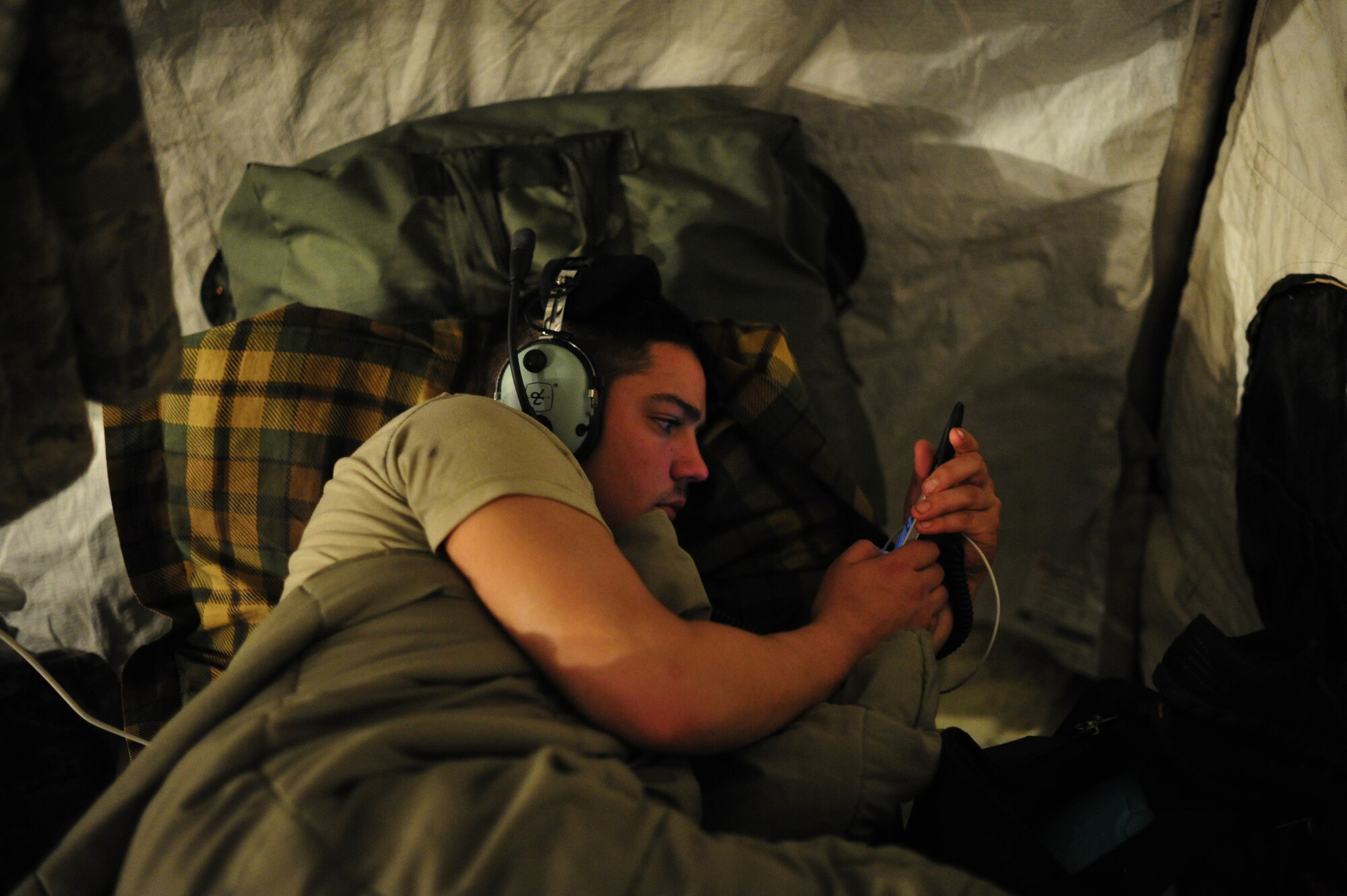 JOINT BASE MCGUIRE-DIX-LAKEHURST, N.J. -- U.S. Air Force Airman 1st Class Jeffery Wood, aircraft maintenance journeyman assigned to the 621st Contingency Response Wing at JB MDL, rests in his cot after a 12-hour shift during Eagle Flag 13-2 March 21, 2013. The camp for the Airmen was established close the base’s active runway, and the constant arrival and departure of C-17 Globemaster III airlifters made it difficult to sleep.  (U.S. Air Force photo by Tech. Sgt. Parker Gyokeres/Released)