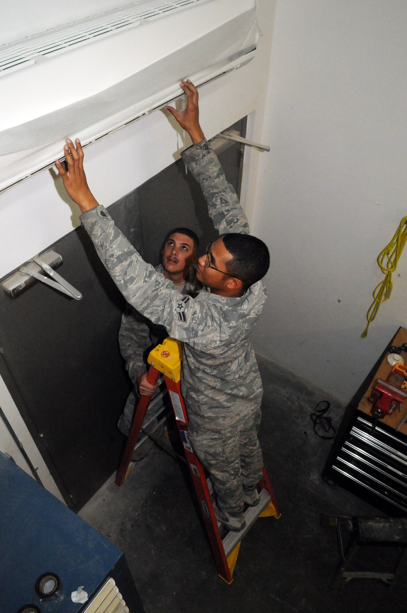 SOUTHWEST ASIA -- Airman 1st Class Jeremiah May and Senior Airman Brian Munson install the indoor fan unit on a split system for the fire department, March 21. The 379th Expeditionary Civil Engineer Squadron Heating Ventilation Air Conditioning / Refrigeration shop maintains all wing and tenant HVAC/R systems on base. (U.S. Air Force photo/Master Sgt. Christian Michael)