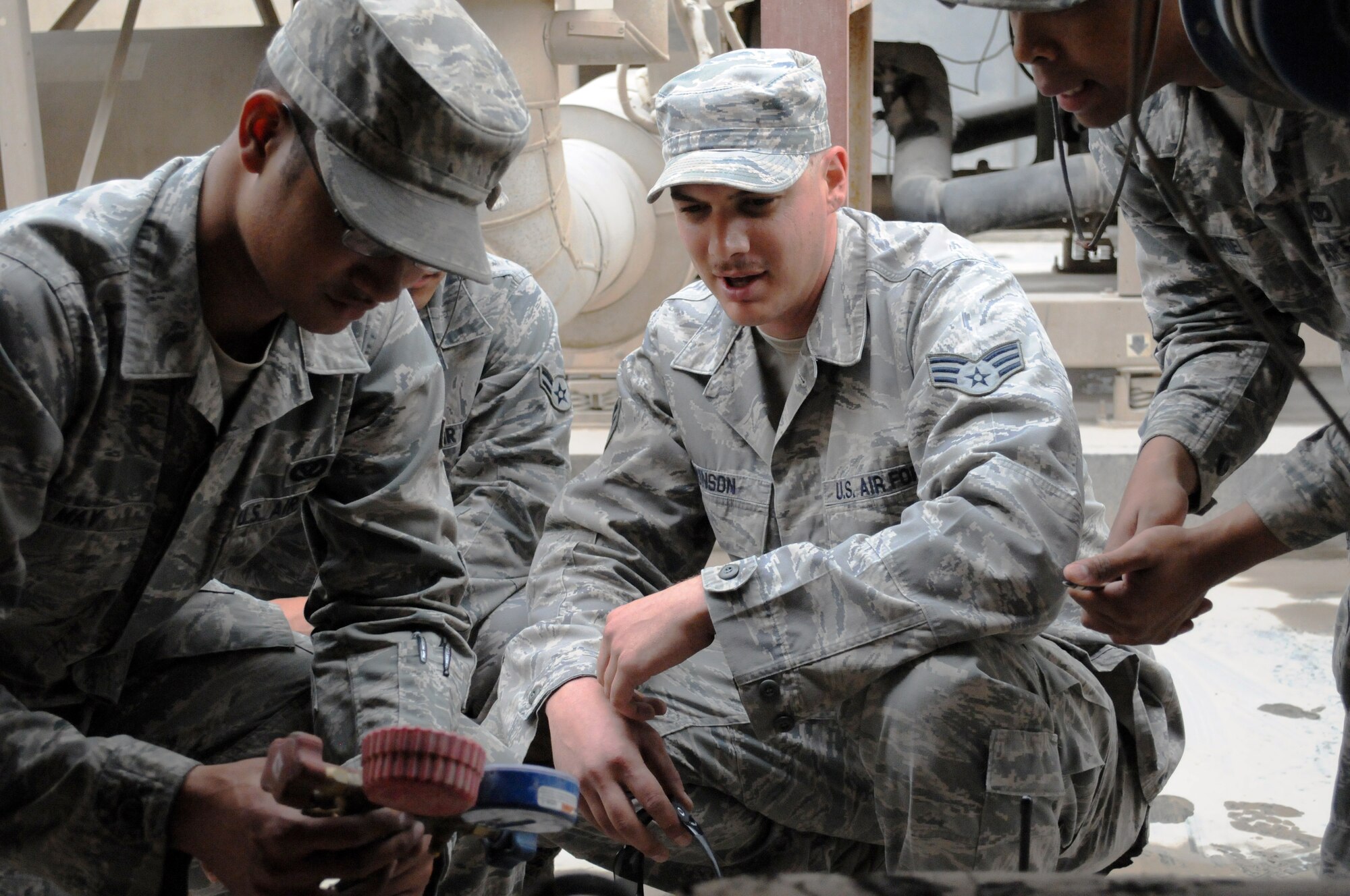 SOUTHWEST ASIA -- Airman 1st Class Jeremiah May checks the refrigerant pressures for the chiller at the Blatchford-Preston Complex Mall while Senior Airmen Brian Munson and David Murriel look on, March 21. The 379th Expeditionary Civil Engineer Squadron Heating Ventilation Air Conditioning / Refrigeration shop maintains all wing and tenant HVAC/R systems on base. (U.S. Air Force photo/Master Sgt. Christian Michael)
