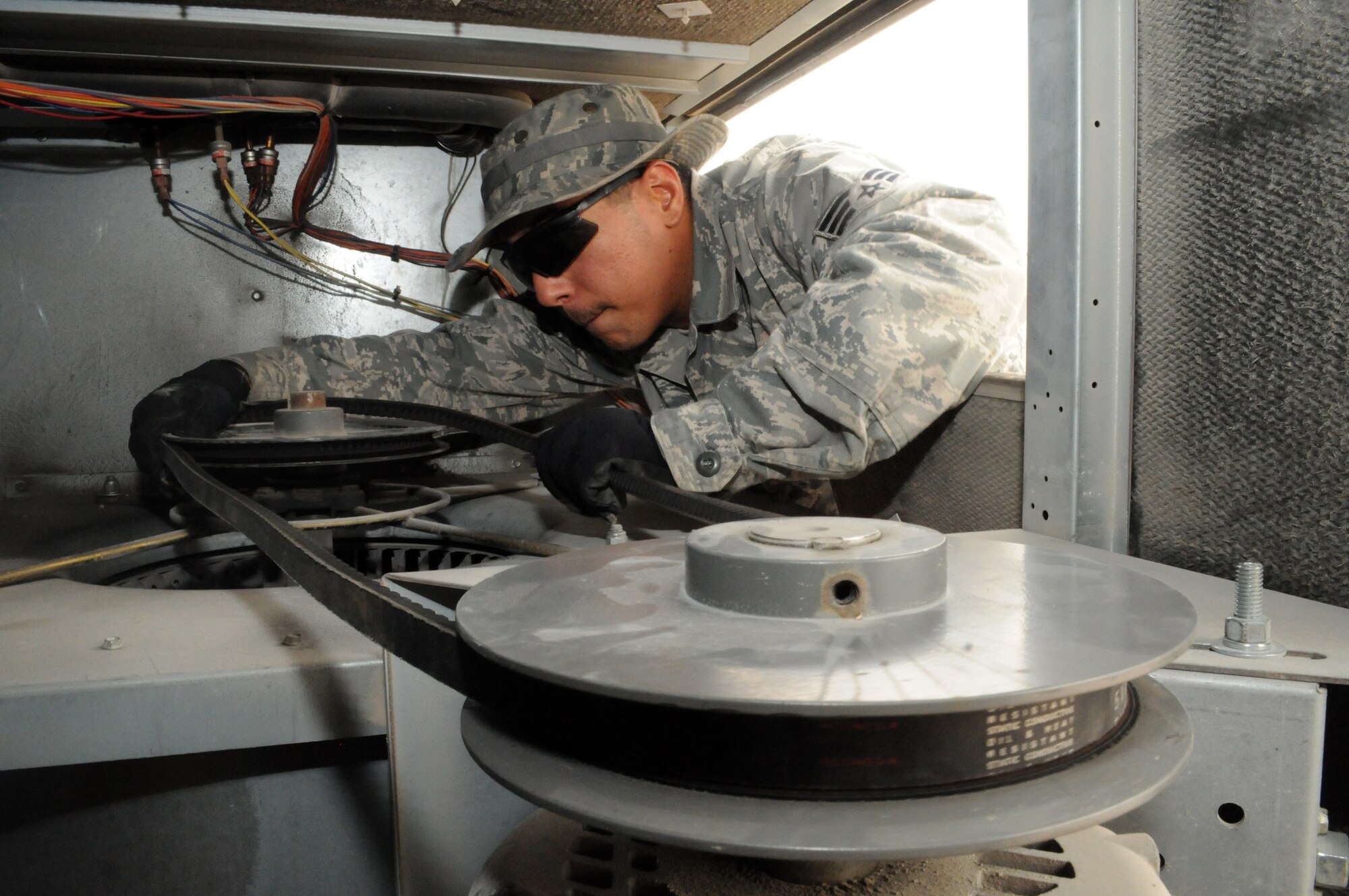 SOUTHWEST ASIA -- Senior Airman Dick Rodriguez replaces a broken fan belt found while doing recurring maintenance on an air conditioning unit, March 21. The 379th Expeditionary Civil Engineer Squadron Heating Ventilation Air Conditioning / Refrigeration shop maintains all wing and tenant HVAC/R systems on base. (U.S. Air Force photo/Master Sgt. Christian Michael)