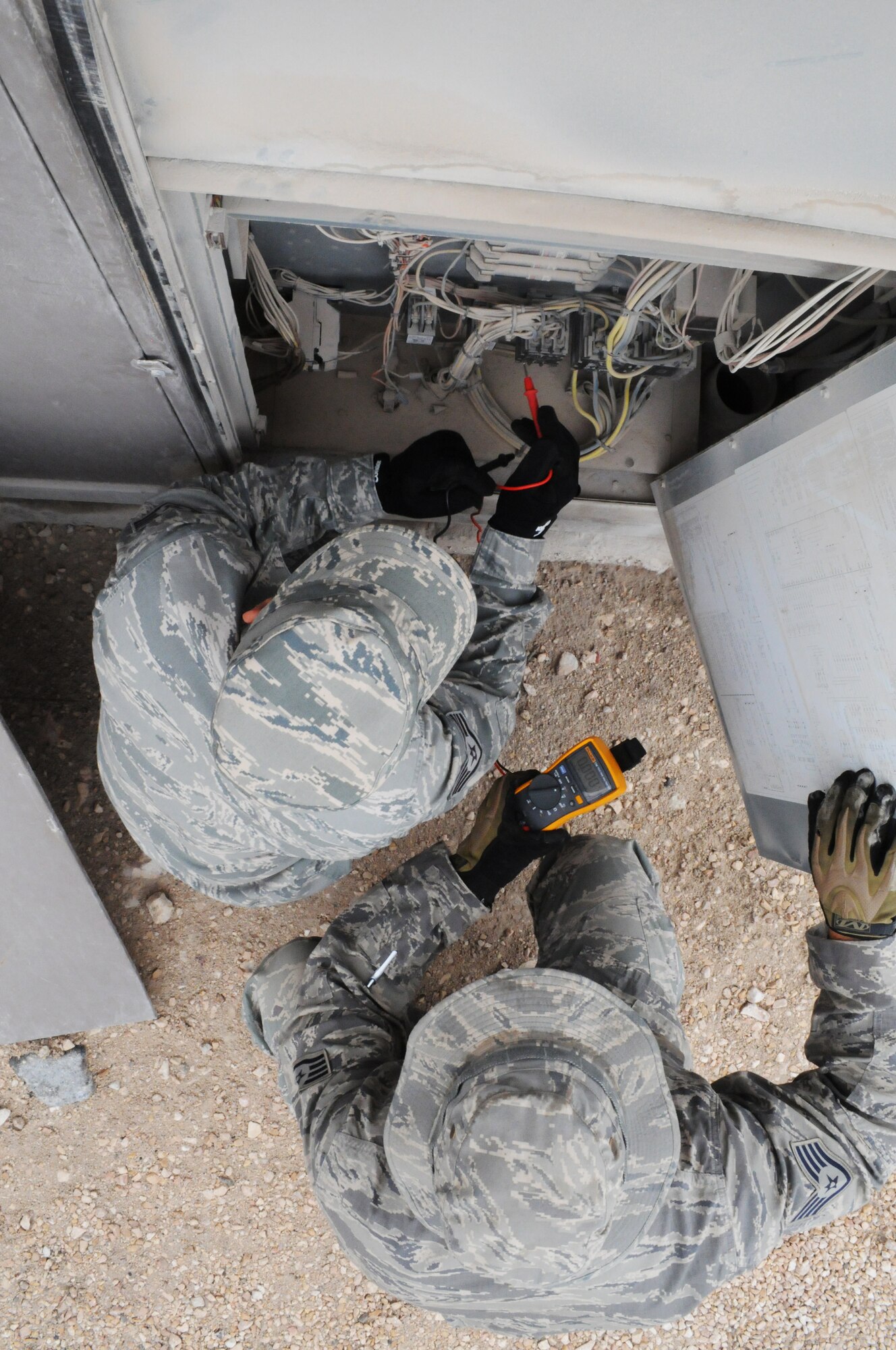 SOUTHWEST ASIA -- Staff Sgts. Ronulfo Dipasupil and James Upton troubleshoot the electrical components on an air conditioning package unit, March 21. The 379th Expeditionary Civil Engineer Squadron Heating Ventilation Air Conditioning / Refrigeration shop maintains all wing and tenant HVAC/R systems on base. (U.S. Air Force photo/Master Sgt. Christian Michael)