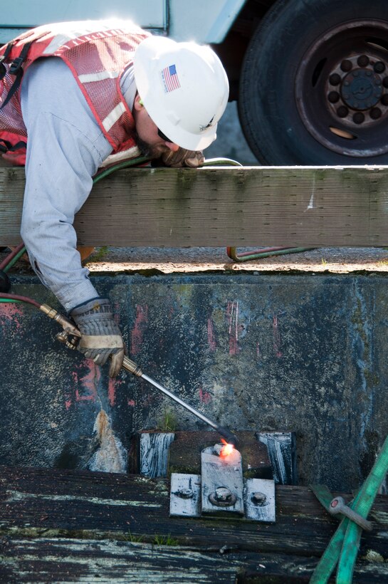 A Port of San Francisco employee uses a blow torch to cut a rotted piling free from Pier 23.