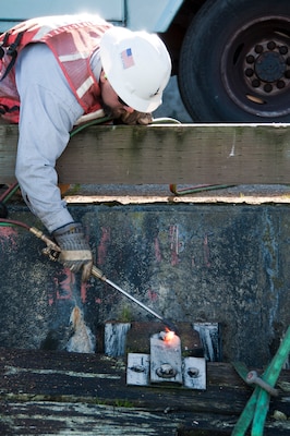 A Port of San Francisco employee uses a blow torch to cut a rotted piling free from Pier 23.