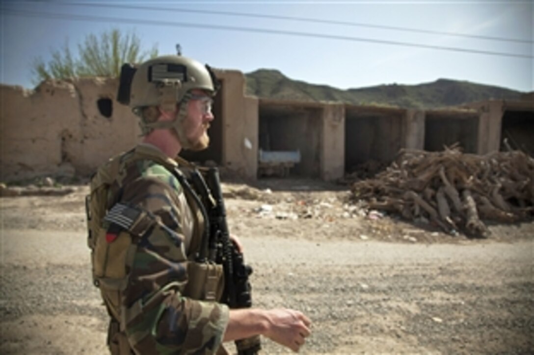 A coaliton force member walks through a bazaar during a presence patrol with Afghan national security forces to escort a district governor in Helmand province, Afghanistan, March 17, 2013.