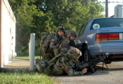 Indiana Army National Guard Soldiers take cover from a rooftop sniper during an early-morning, XCTC 2006 training exercise at the Muscatatuck Urban Training Center in Indiana in late July.