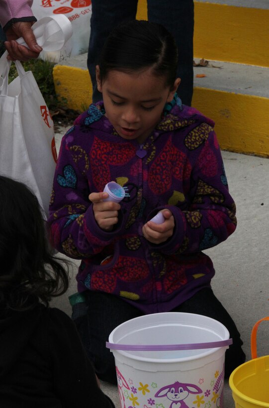 The daughter of a Marine with Combat Logistics Battalion 6, 2nd Marine Logistics Group opens a plastic egg during an event hunt held for the unit’s families aboard Camp Lejeune, N.C., March 23, 2013. The children discovered candy and small toys inside the Easter eggs