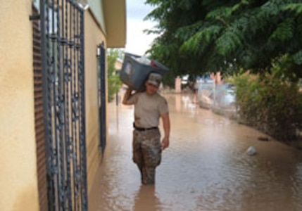 A Texas National Guard Soldier helps a resident of Vinton, Texas, with some belongings after rising water swamped homes in the small west Texas town.