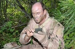 Lt. Col. Gus Kohntopp applies camouflage face paint to avoid being spotted by the enemy during the Idaho Air National Guard's combat survival training exercise near Idaho City, Idaho, on Aug. 6.