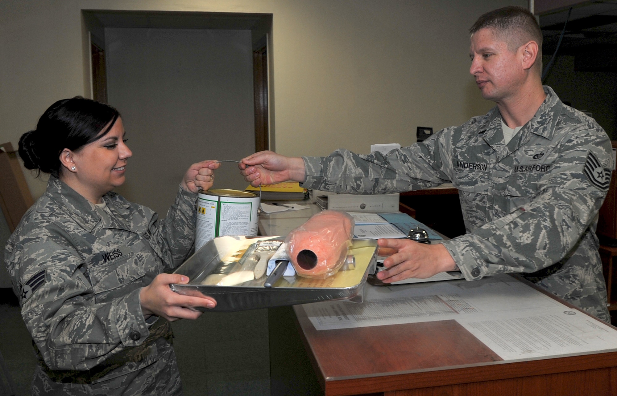 Tech. Sgt. Tony Anderson, right, 51st Civil Engineer Squadron Mongrel Self Help Store NCO in charge,  gives paint supplies to Senior Airman Kimberlie Weiss, 51st CES operations support section customer service representative, at the Mongrel Self Help Store in Bldg. 657 on Osan Air Base, Republic of Korea, March 28. Airmen and dependents can utilize the self-help store for items needed to repair minor issues in dorms and base facilities. (U.S. Air Force photo/Senior Airman Kristina Overton)