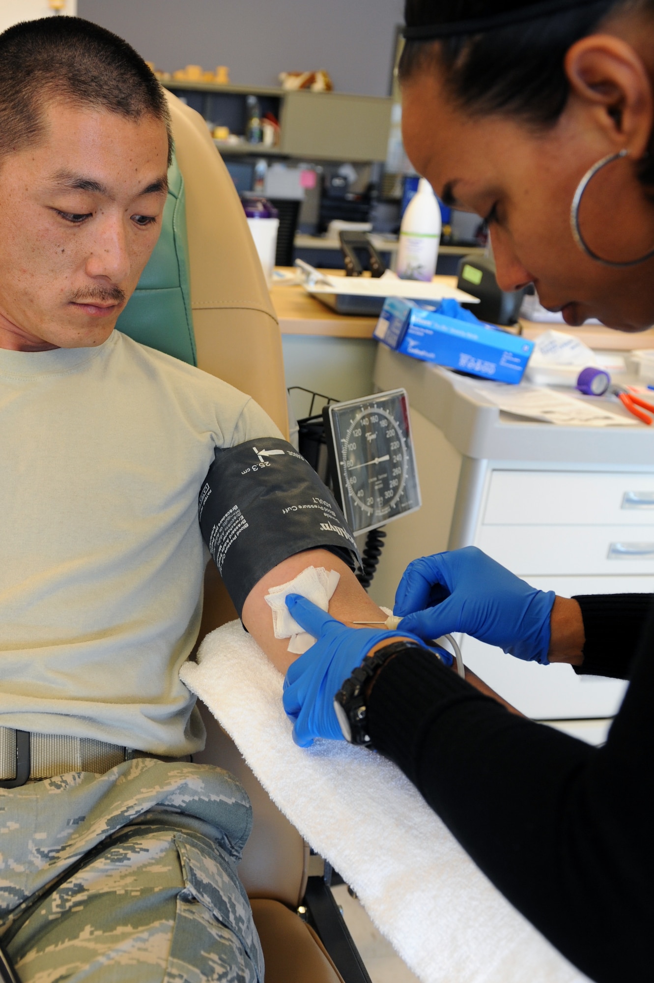 Tech. Sgt. Craig Kim, 460th Space Communications Squadron, watches a nurse insert a needle into his arm March 20, 2013, at the Children's Hospital Colorado in Denver. The 460th SCS participated as a group to donate to the children’s hospital. The hospital is always in need of a wide range of blood products the children need. (U.S. Air Force photo by Senior Airman Marcy Glass/Released)