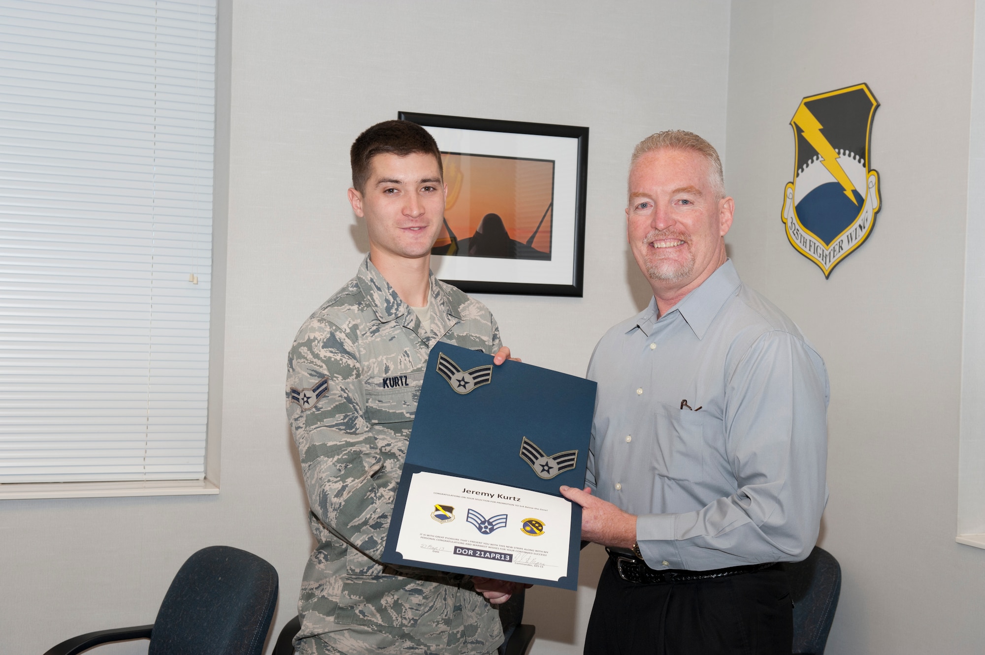 Airman 1st Class Jeremy Kurtz, 325th Communications Squadron radio frequency technician, is notified of her below-the-zone promotion by Mr. Dan Moran, 325th CS deputy director, March 27. The BTZ program allows those in the rank of Airmen 1st Class to be promoted to Senior Airmen six months before they normally would. (U.S. Air Force photo by Lisa Norman)