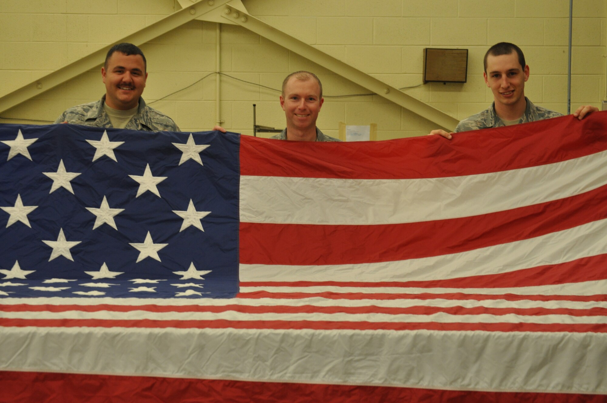 Staff Sgt. Joshua Nelson, 325 Operations Support Squadron Aircrew Fighter Equipment, Tech Sgt. Jamie Smith, 43rd Fighter Squadron the previous parachute shop NCO in charge, and Airman 1st Class Tomas Mitchell, 325 OSS aircrew flight equipment technician, hold up an American flag on March 21 in Hanger 5 on Tyndall Air Force Base. They, along with their colleagues, repair the flags on base in an effort to keep Tyndall’s flags in good shape and save the funds a replacement flag would cost. (U.S. Air Force photo by Airman 1st Class Alex Echols)
