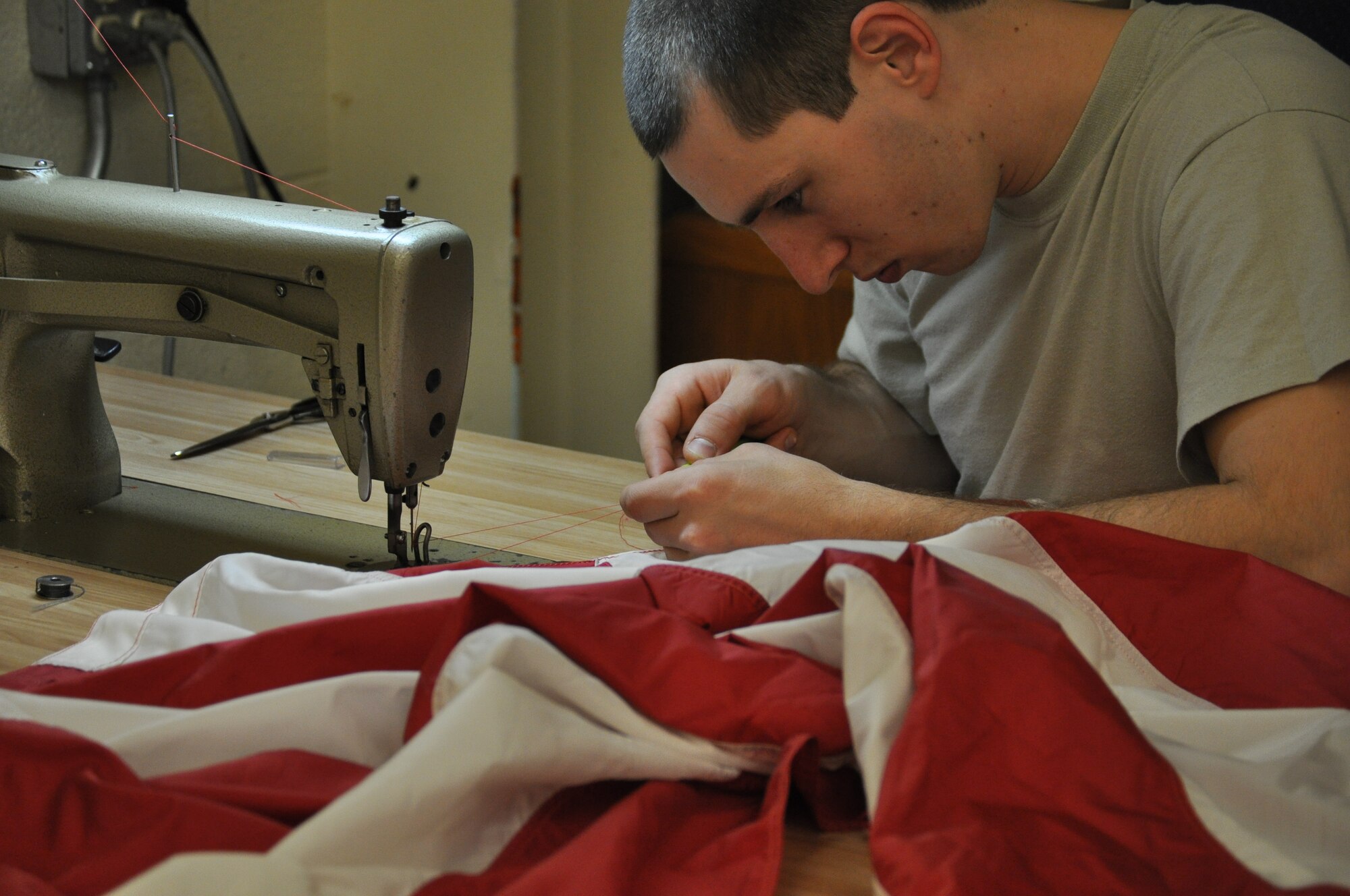 Airman 1st Class Tomas Mitchell, 325 Operations Support Squadron aircrew flight equipment technician, repairs a base flag on March 21 in Hanger 5 on Tyndall Air Force Base. He and his colleagues are tasked with the repair of the flags on base in an effort to keep Tyndall’s flags in good shape and save the funds a replacement flag would cost. (U.S. Air Force photo by Airman 1st Class Alex Echols)