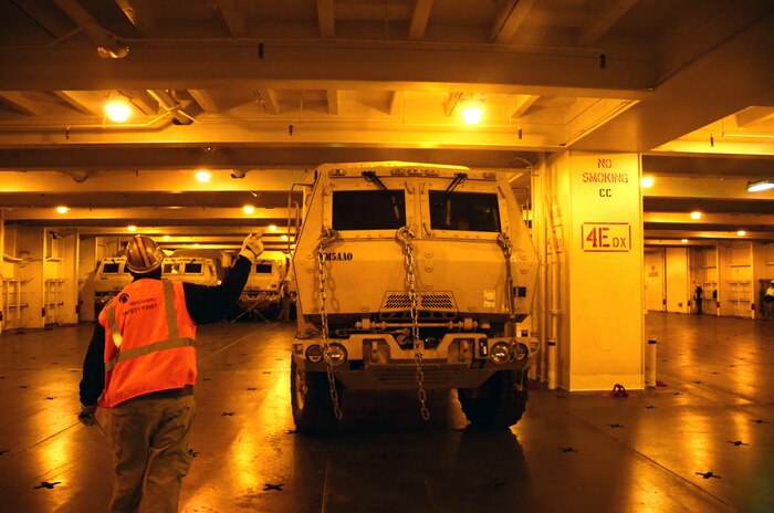 A flagman from Ports America  directs a vehicle into position during the loading of the USNS Soderman (T-AKR 317) March 22, 2013, at Wharf Alpha on Joint Base Charleston - Weapons Station, S.C.  The nine-deck ship will carry more than 1,600 military vehicles and 160 shipping containers after being loaded and will be prepositioned overseas. (U.S. Air Force photo/Staff Sgt. William O'Brien)
 
