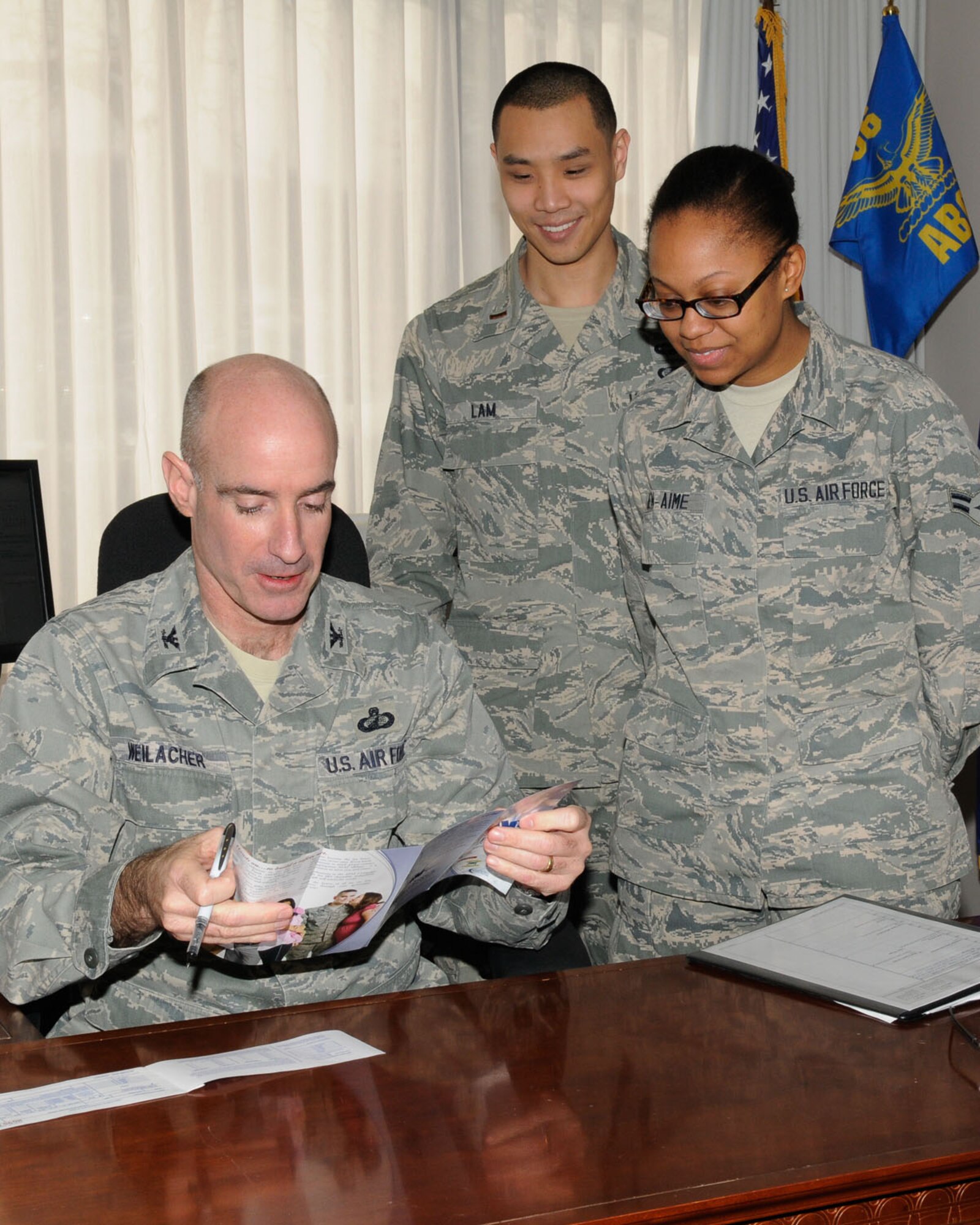 HANSCOM AIR FORCE BASE, Mass. – Col. Lester A. Weilacher, 66th Air Base Group commander, discusses Air Force Assistance Fund information before signing his contribution form with Airman 1st Class Sabine Bien-Aime and 2nd Lt. David Lam, unit and installation project officers, March 25. The base’s AFAF campaign continues through May 3. (U.S. Air Force photo by Linda LaBonte Britt) 