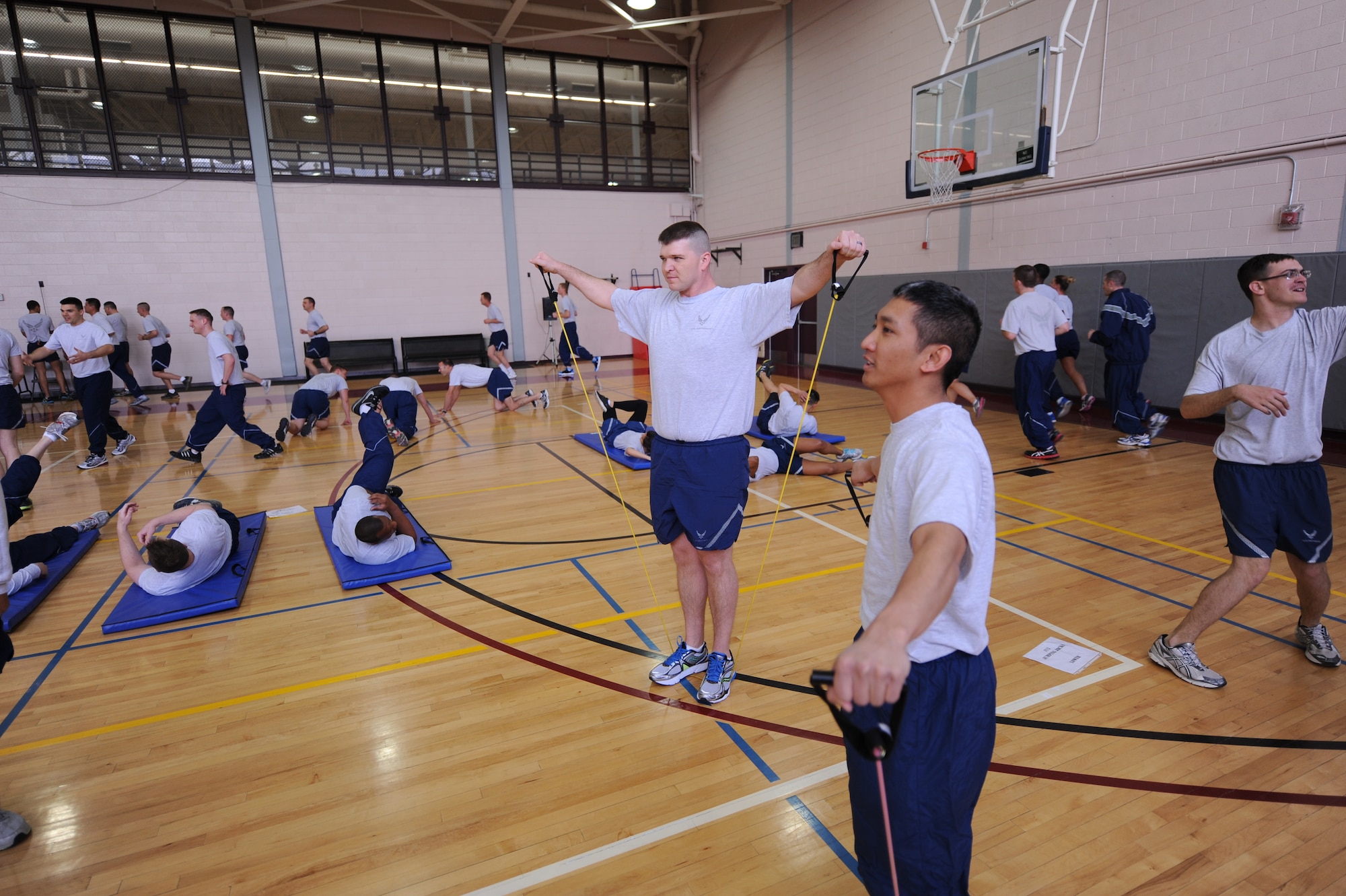 Tech. Sgt. Harold Morris, middle, 21st Space Wing ground safety technician and Staff Sgt. Edward Guiang, right, 21st SW space safety technician, use bands to work out their shoulders May 26 during Wing Warfit at the Peterson Sports and Fitness Center.  The monthly workout session for all 21st Space Wing members consisted of a warm-up, 20 minutes of running, 20 minutes of strength exercises and a cool-down. (U.S. Air Force photo by Senior Airman Jacob Morgan)