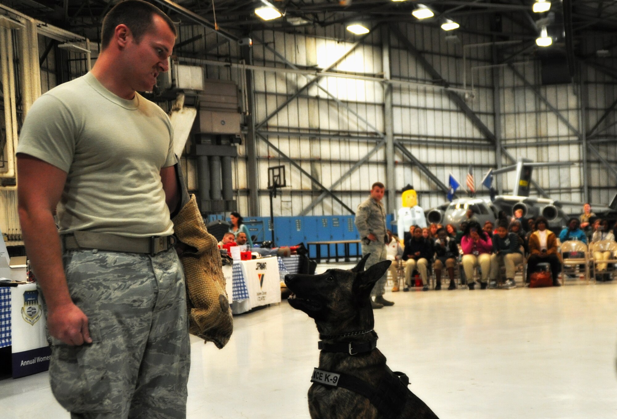 A member of the 628th Security Forces Squadron performs a K-9 demonstration at Joint Base Charleston, SC, March 26. Nearly 140 eighth and ninth grade-girls from Charleston area schools visited to learn about jobs in aviation. (U.S. Air Force photo/Tech. Sgt. Scott Mathews)