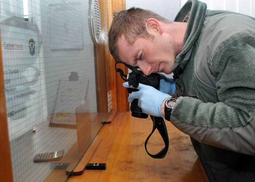 Tech. Sgt. Michael Crawford, 100th Security Forces Squadron investigator, takes photos of a partial fingerprint during an exercise March 26, 2013, at RAF Mildenhall, England. Crawford, a native of Elkhart, Texas, was part of a crime scene response team for a simulated robbery during the exercise. (U.S. Air Force photo by Airman 1st class Kelsey Waters/Released)