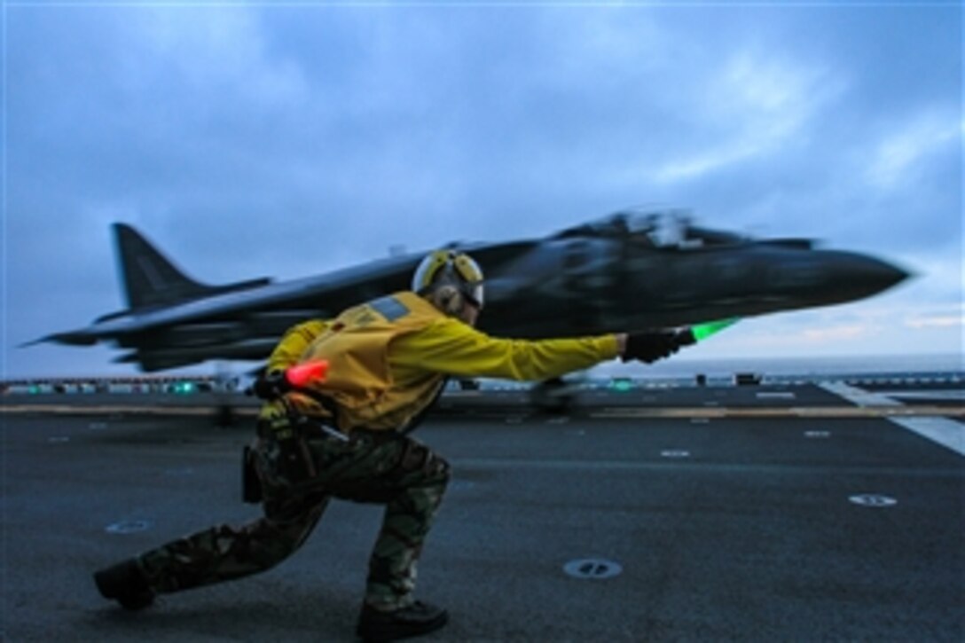 A flight deck crewman clears an AV-8B Harrier to take off during flight operations aboard the amphibious assault ship USS Boxer (LHD 4) as the ship conducts training in the Pacific Ocean off the coast of Southern California on Mar. 25, 2013.  The Harrier is attached to Marine Attack Squadron 214.  