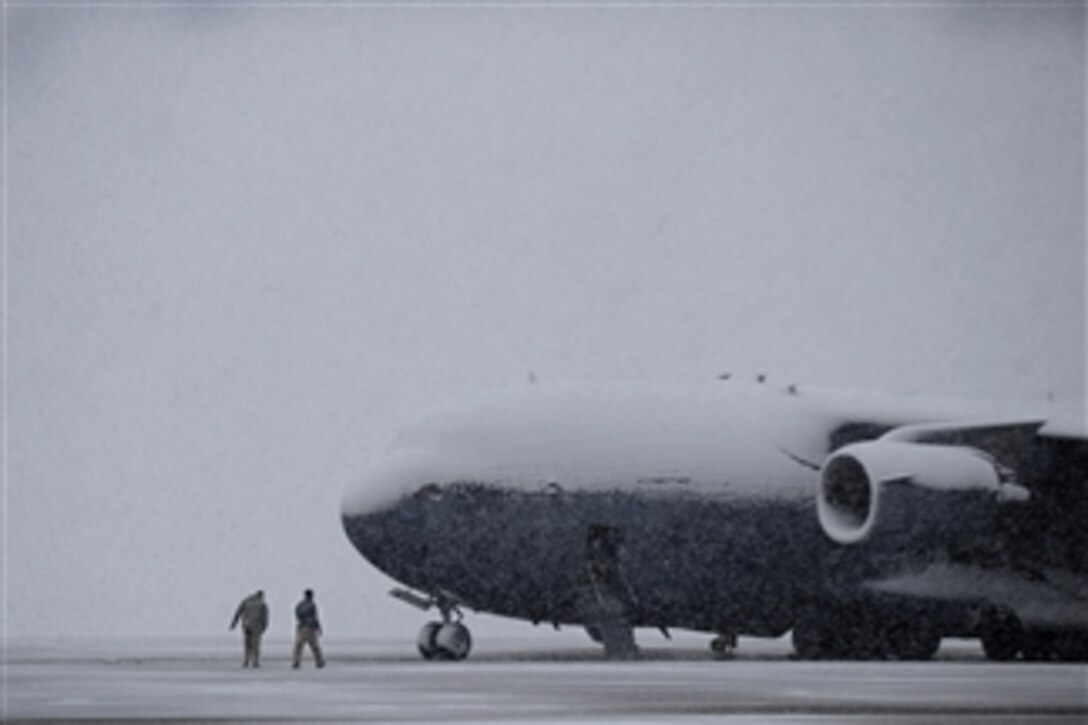 Crewmembers walk through the snow to a U.S. Air Force C-17 Globemaster III parked on the ramp at Joint Base Andrews, Md., on March 25, 2013.  