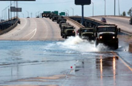 A convoy of military vehicles cross floodwaters on IH-10 to move Texas Air National Guard Security Forces Squadrons (SFS) on September 10th, 2005. The squadrons were being moved from Francis Gaudet Elementary School to Loyola University to provide additional search and rescue missions in New Orleans, Louisiana, in the aftermath of Hurricane Katrina.