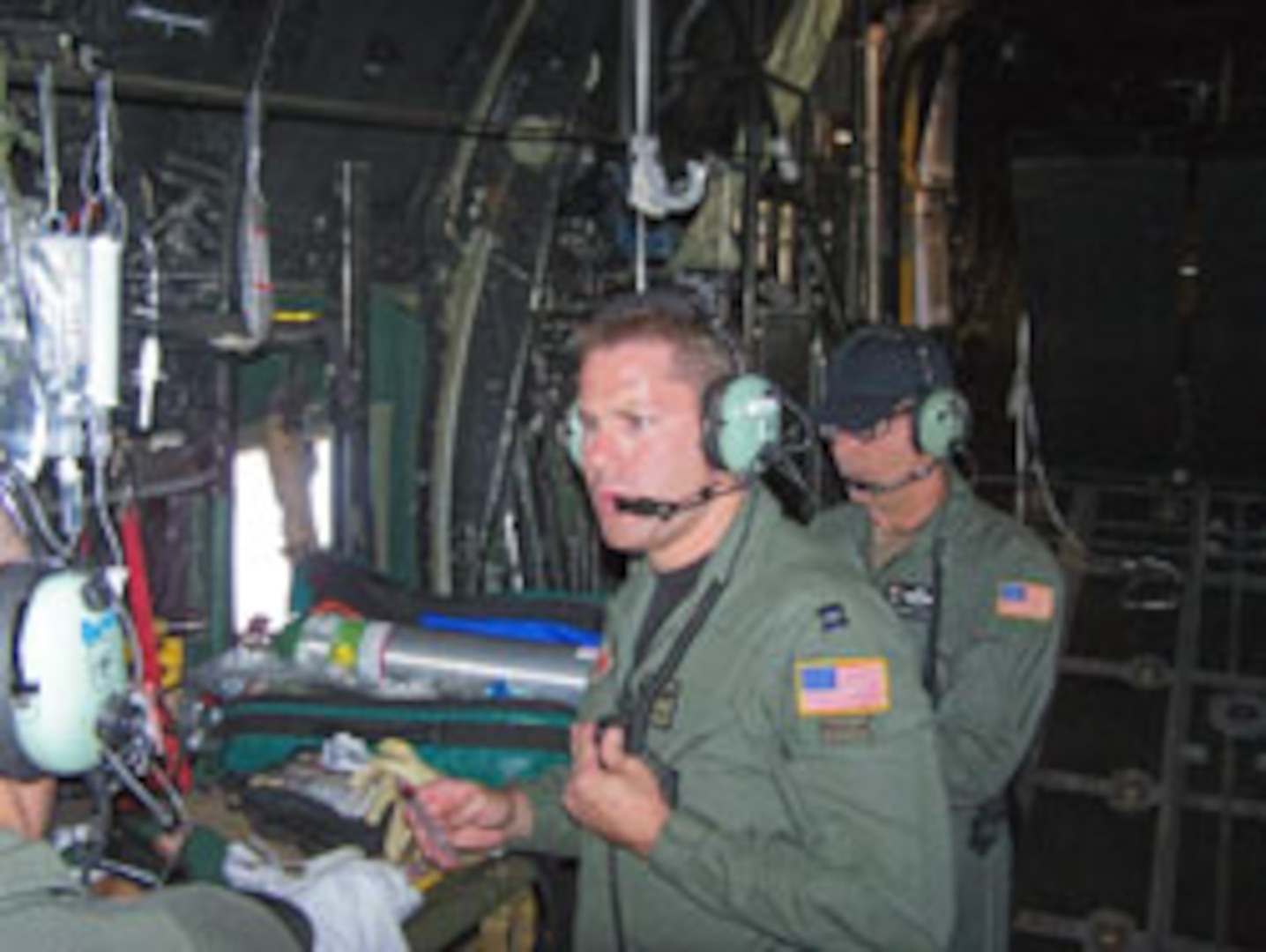 129th Rescue Wing flight surgeon,. Maj. (Dr.) Joshua S. Kucker, center, and MC-130P loadmaster, Senior Master Sgt. William J. Wunderlin, right, treats and assists one of the critically injured children during the flight to Naval Air Station North Island, CA.