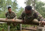 Spc. Dan Bounnavong, Troop C, 2nd Squadron, 106th Cavalry, and a British Soldier with Number 7 Company, Coldstream Guards go over an obstacle together as part of a training exercise between the United States and Great Britain at Ft. McCoy, Wis. in July. As part of transformation, the new unit is able to participate in a variety of new training opportunities.