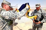 Army Col. Stephen Williams (left) commander of the 207th Infantry Brigade, Alaskan National Guard, and Command Sgt. Maj. Robert Averett (right) also with the ANG, unfurl their flag assuming command of the U.S. National Command Element in Southern Afghanistan here July 2. (Photo by Army Staff Sgt. Brian Raley)