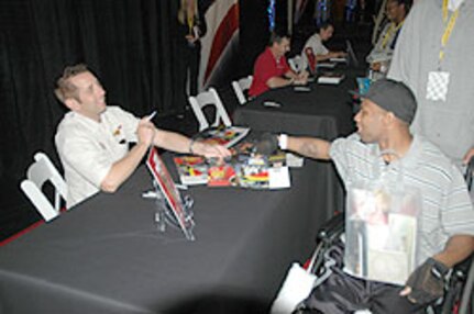 NASCAR driver Greg Biffle, who drives the No. 16 National Guard-sponsored car, hands out autographed posters at Walter Reed Army Medical Center Sept. 21 to patients and families.  Biffle, was one of several NASCAR drivers who visited patients that day.