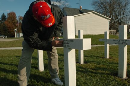 Jerry Jodrey, a retired Army master sergeant and president of the Ohio Fallen Heroes organization, wipes dirt from a marble cross representing Army Spc. Allen J. Vandayburg at the Ohio Fallen Heroes memorial park Nov. 3.