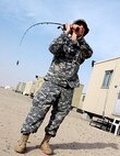 Sgt. Melinda Hooper, a flight operations specialist with the 114th Aviation Regiment of the Arkansas National Guard, practices casting her fishing line into the desert. With no lakes or rivers to fish, Hooper relies on the open desert terrain as her means of practice.