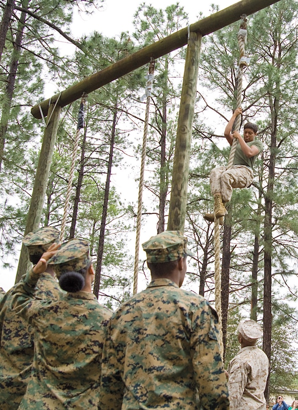 Marines demonstrate how to properly climb the obstacle course’s rope climb to Marine and Navy Junior Reserve Officer Training Corps cadets here, March 19. The students put their training to the test by attempting all the course’s obstacles with Marines right by their side.