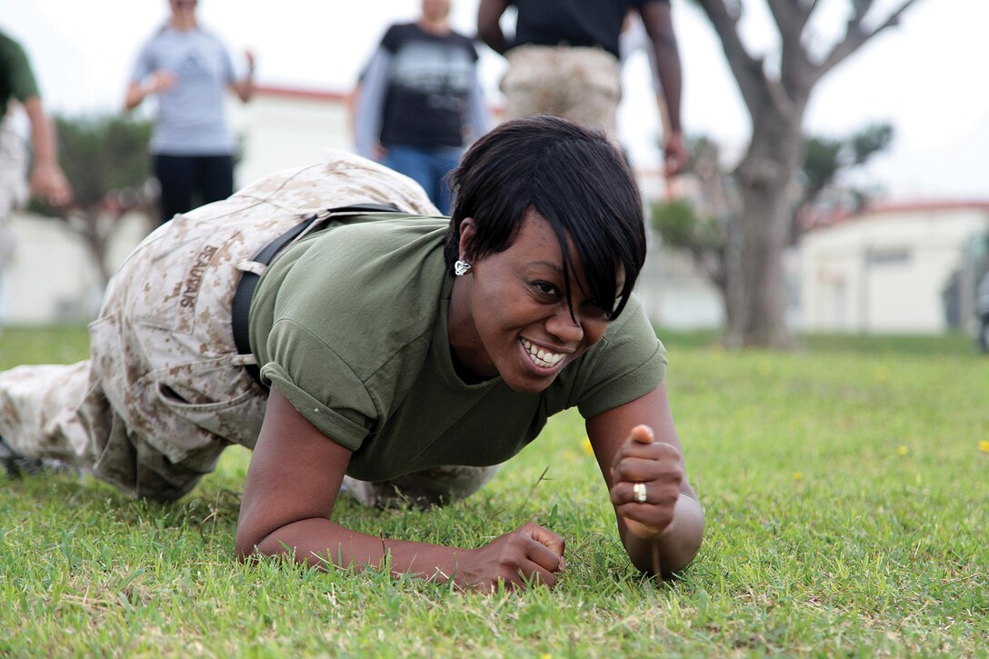 Myrlaine Beauvais low-crawls across a field as part of the Marine Corps martial arts program station during a Jane Wayne day March 22 at Marine Corps Air Station Futenma.  Marine Aircraft Group 36, 1st Marine Aircraft Wing, III Marine Expeditionary Force, hosted the event. 