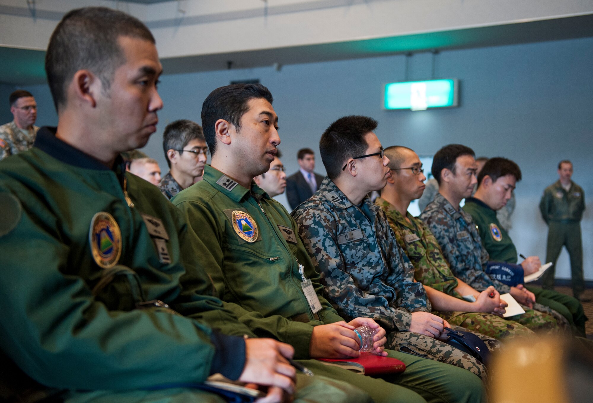 Japan Air Self-Defense Force service members listen to a briefing while observing a simulated noncombatant evacuation operation at the Taiyo Recreation Center March 28, 2013, at Yokota Air Base, Japan.  Yokota service members showcased their NEO capabilities in an effort to strengthen bilateral relations with JASDF counterparts. (U.S. Air Force photo by Senior Airman Cody H. Ramirez)