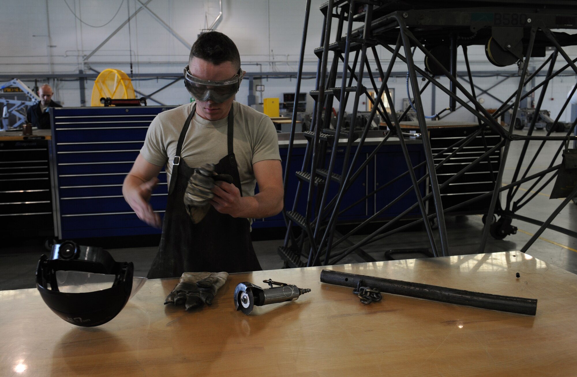 Airman 1st Class Sean Matkosky, 2nd Maintenance Squadron Aerospace Ground Equipment flight, removes his personal protection equipment after sawing off a broken piece of metal from a B-5 stand on Barksdale Air Force Base, La., March 28. AGE is responsible for maintaining the equipment used by maintainers to get aircraft off the ground and in the air. (U.S. Air Force photo/Airman 1st Class Benjamin Gonsier)