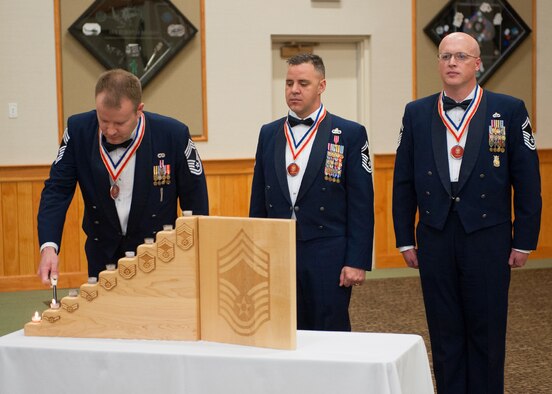 Chief Master Sgt. Daniel Willand, 341st Maintenance Group superintendent, lights the first few candles during the candle lighting ceremony. Senior Master Sgt. Jared Klingaman, 341st Security Forces Squadron manager and Senior Master Sgt. David Clifford, 341st Missile Wing installation fire chief look on. (U.S. Air Force photo / Beau Wade)
