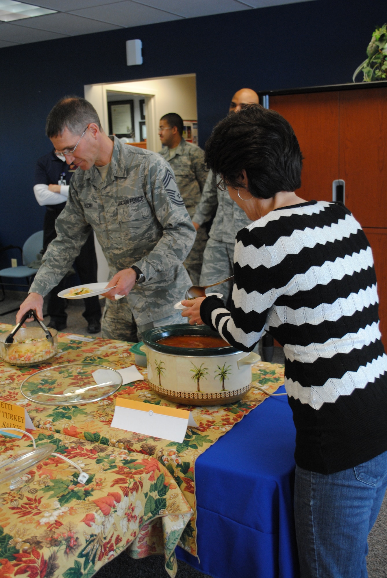 Ellen Fidani; wife of Chief Master Sgt. Frank Fidani, 341st Missile Wing command chief; and Chief Master Sgt. Duane Buchi, 341st Mission Support Group superintendent, dish out servings of two of the entered recipes in the HAWC’s “Eat Right, Your Way, Every Day” Recipe Challenge.  Fidani and Buchi were two of four members judging the recipes March 22; the others were Lt. Col. Marco Galvez, 341st Medical Operations Squadron member, and Lt. Col. James Tanner, 341st MDOS chief of physical therapy.  (U.S. Air Force photo/Senior Airman Cortney Paxton)