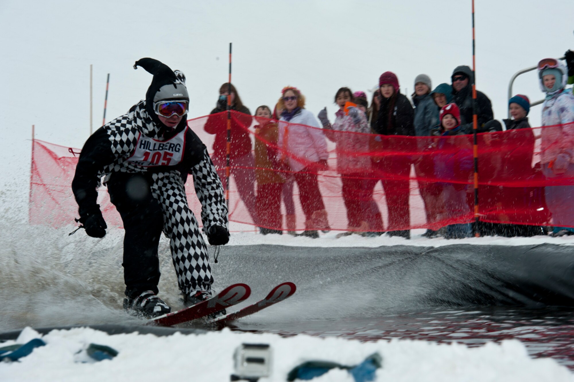 JOINT BASE ELMENDORF-RICHARDSON, Alaska -- Kevin Kulp, dressed as a jester, jets across a man-made pool of water at the Hillberg Slush Cup March 24. Kulp was one of the few contestants to actually make it across the large span of water. The Slush Cup is an annual event event held at the Hillberg Ski Area on JBER. (U.S. Air Force photo/Airman 1st Class Omari Bernard)