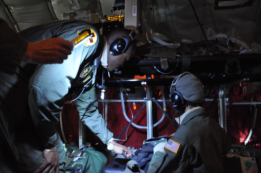 Staff Sgt. Khai Davis and Senior Airman Jasmine Simms, Critical Care Air Transport Team members with the 459th Aeromedical Staging Squadron at Joint Base Andrews, Md., use a flashlight to navigate their way around the medical bags during a training mission to Texas and California, March 22, 2013. The CCATT teamed up with the 459th Aeromedical Evacuation Squadron to get experience working together and to learn the ins and outs of taking care of patients while airborne. The two teams fly together once every three months. (U.S. Air Force photo/ Staff Sgt. Katie Spencer)