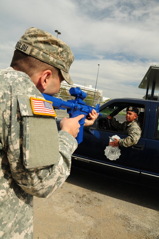 SPC Karoglou, a telephone operator assigned to the California State Military Reserves, 2nd Battalion, Alpha Company challenges a vehicle that contains an armed suspect, at Moffett Federal Airfield, Calif., March 2, 2013. Karoglou, is being trained by Senior Airman Roberto Alvarez of the 129th Security Forces Squadron on vehicle challenge procedures. This group of CSMR soldiers are training to provide support to the Air National Guard during riots, natural disasters and deployments. (Air National Guard photo by Staff Sgt. Kim E. Ramirez)




