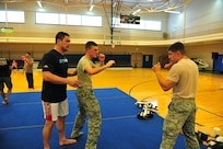 Ultimate Fighting Championship fighter Shane Del Rosario teaches 1st Lt. Steve Arthur and Senior Airman Joshua Royer how to perform certain moves while sparring during a UFC demo event March
15 at Joint Base San Antonio-Randolph. (U.S. Air Force photo by Airman 1st Class Colville McFee/ Released)