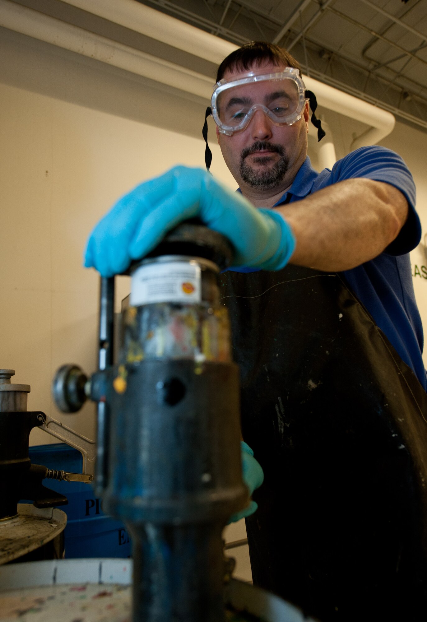 Keith LeBlond, Chenega Global Services, LLC hazardous material warehouse technician, releases pressure from aerosol cans during the recycling process at Ellsworth Air Force Base, S.D., March 22, 2013. HAMART saved more than $2,500 recycling aerosol cans and small cylinders in 2012. (U.S. Air Force photo by Airman 1st Class Alystria Maurer/Released)