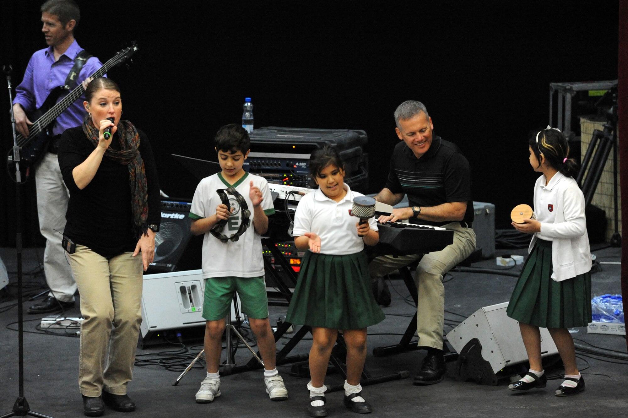Tech. Sgt. Paige Martin, vocalist for the U.S. Air Forces Central Command Band “Vector” is aided by students during their performance at a host nation school in Southwest Asia Mar 28, 2013. The AFCENT Band tours throughout the AOR to positively promote troop morale, diplomacy and outreach to host nation communities. (U.S. Air Force photo by Senior Master Sgt. George Thompson)