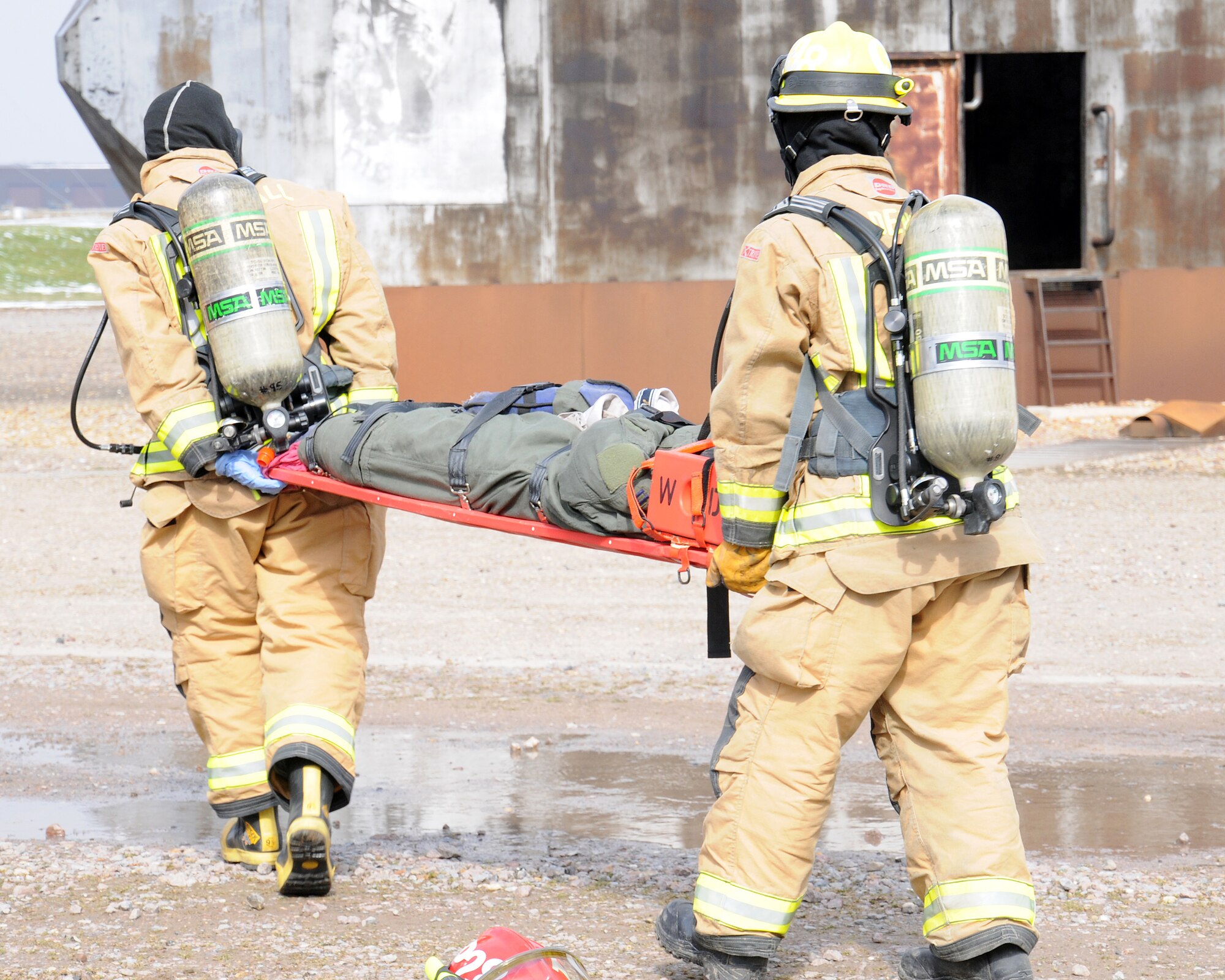 100th Civil Engineer Squadron Fire Department firefighters move a simulated patient to an ambulance for medical care during an exercise March 25, 2013, at RAF Mildenhall, England. The scenario involved lightning striking a building, which caused a fire. A person ran out of the building and got hit by a car, which then hit another car, turning it upside down and trapping three people. Firefighters prioritized their response, as the vehicle accident was a risk to life, while the building wasn't considered mission-essential. The first responders rescued the simulated victims from the vehicle and transported them to safety until medics appeared on-scene. (U.S. Air Force photo by Gina Randall/Released)
